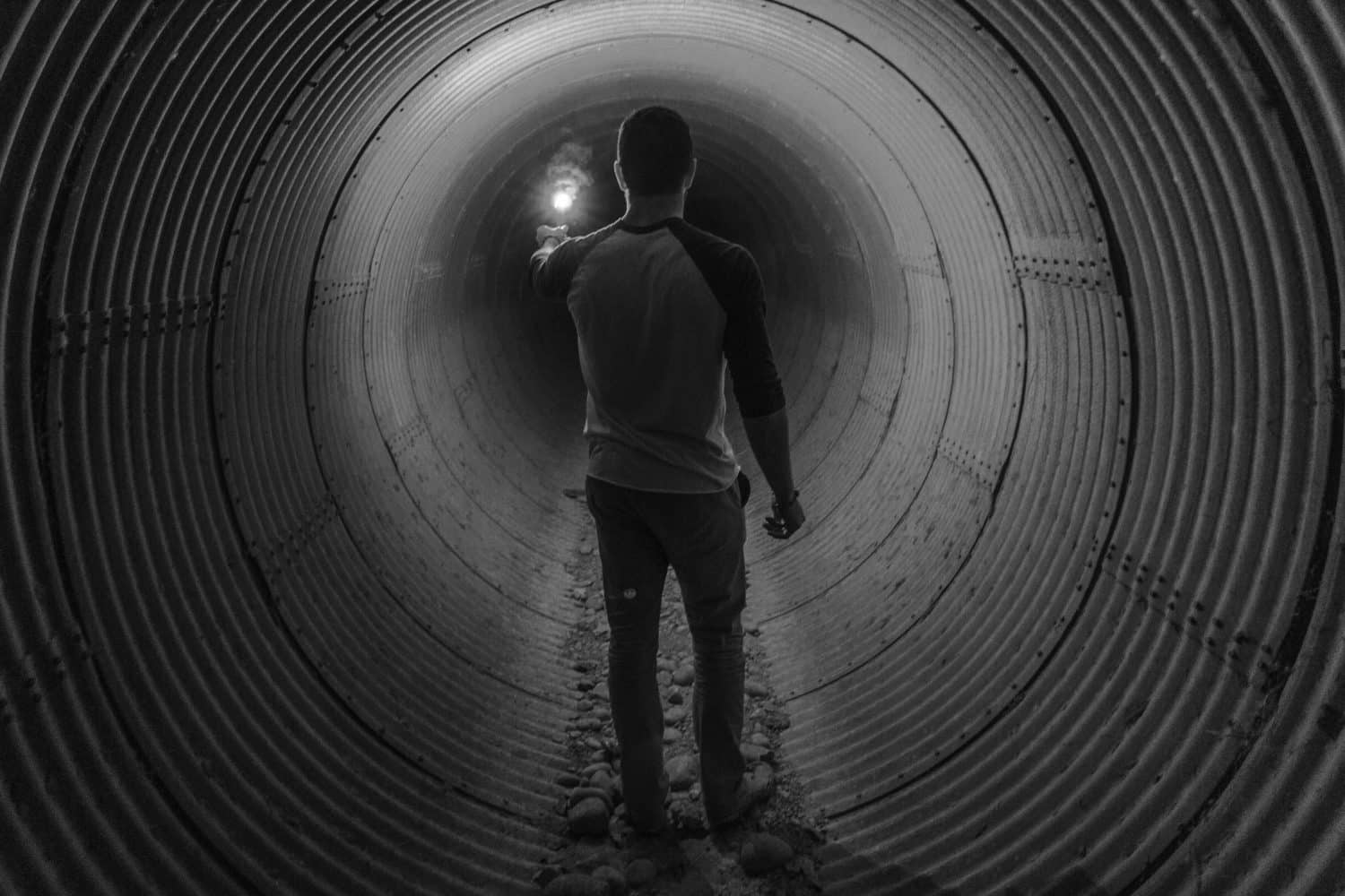 man walking through a light tunnel with flashlight